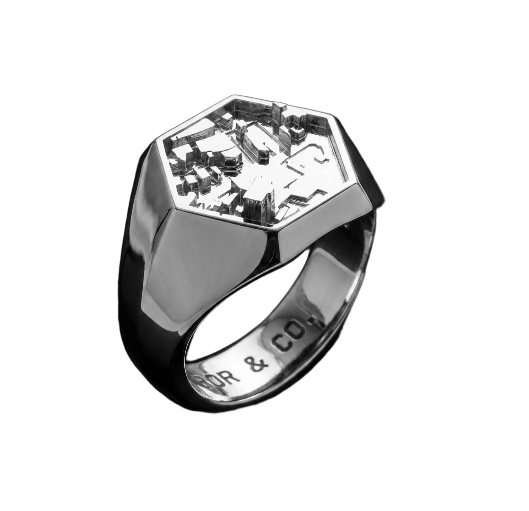 925 sterling silver hexagon signet ring with Shibuya / Tokyo building relief on the table, mirror-polished finish, background removed.